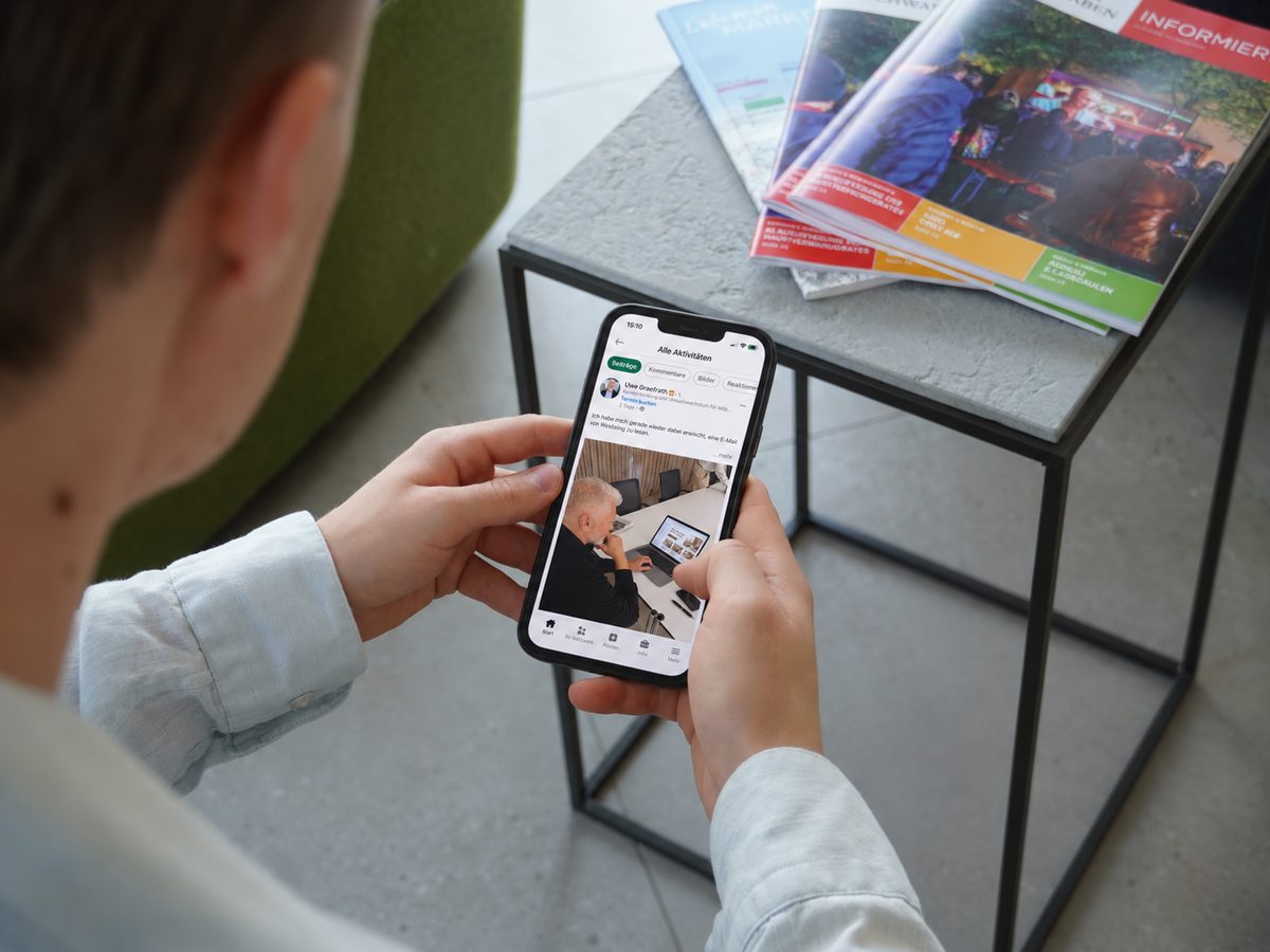 Ein Entscheider liest im Wartebereich einen LinkedIn-Beitrag auf dem Smartphone